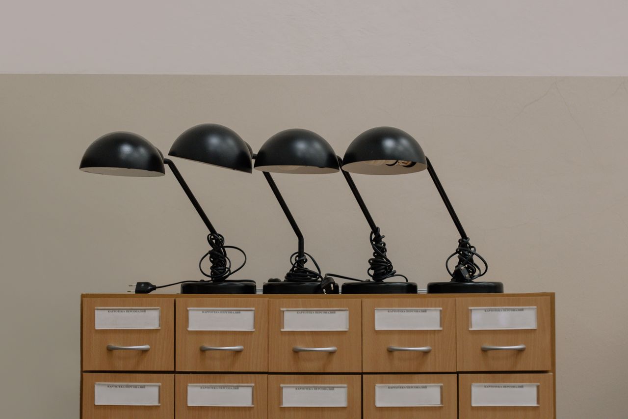 Home Four black retro desk lamps on a wooden cabinet, embodying minimalist design in an elegant interior.