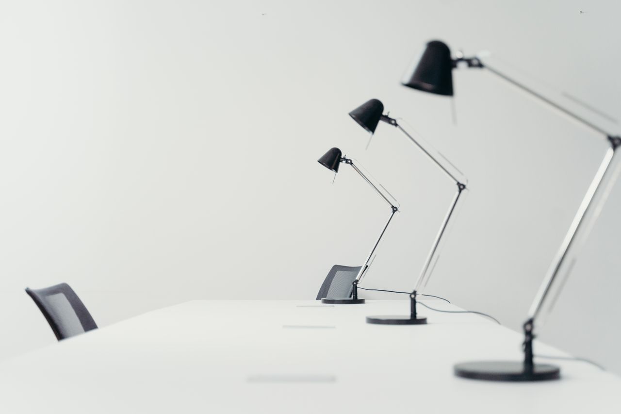 Home Sleek white office setting with modern black desk lamps and chairs, showcasing minimalism.